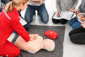 Woman demonstrating CPR on mannequin in first aid class